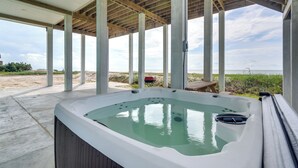 Boblebad under et træbeklædt pergola med udsigt til stranden.