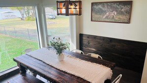 Une chambre avec un lit en bois, un tapis blanc, une plante sur la table de chevet et un tableau au mur.