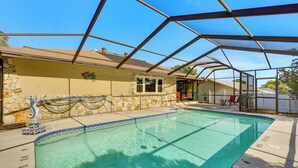 A swimming pool with a glass enclosure, a stone wall, and a clear blue sky. - 5 Mi to Weeki Wachee: Spring Hill Home w/ Lanai (Spring Hill)