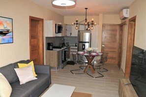 Cozy living space with a kitchenette and dining area, featuring a round table with a unique X-shaped base and modern appliances.