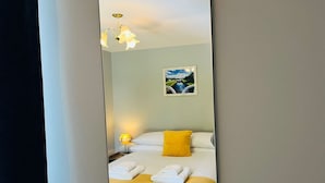 A hotel room with a bed, a nightstand, a lamp, and a framed picture on the wall.