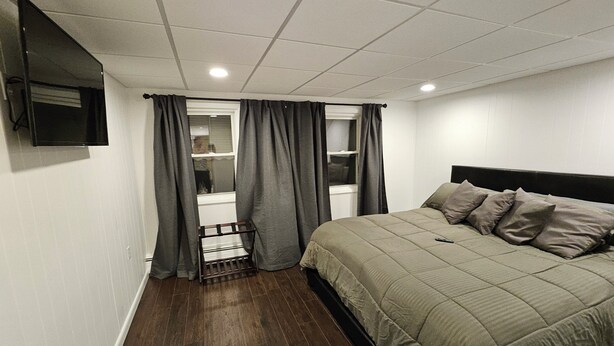 A bedroom with a bed, a TV mounted on the wall, and a window with curtains. - Enjoy easy access to this  4 Bedroom smart home in downtown Hazleton PA.   (Hazleton)