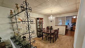 A dining area with a chandelier, a glass display unit, and a dining table with chairs. - Enjoy easy access to this  4 Bedroom smart home in downtown Hazleton PA.   (Hazleton)