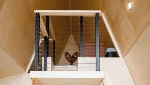 A compact, modern room with a small table and two chairs, a staircase, and a wall-mounted air conditioning unit. - Summit A-Frame (Two Harbors)