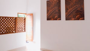 Un pasillo con un separador de madera, una puerta y dos cuadros enmarcados en la pared.