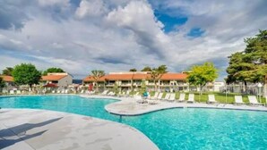 A swimming pool with a curved design, surrounded by lounge chairs and a building with a red roof. - Crescent Bar Condo: On the river with Pool, Gorge shuttle/Wineries, AC (Quincy)