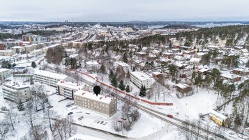 Vista aérea de una ciudad con edificios residenciales y comerciales, una línea de tren y un paisaje cubierto de nieve.
