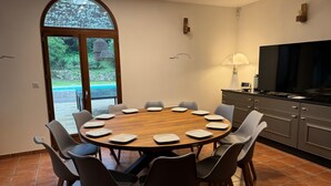 A dining area with a round table, chairs, a TV, and a view through a large window. - "Villa Mammona 500m from Bonifacio harbour (Bonifacio)