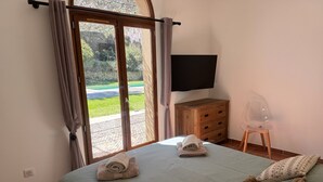 A bedroom with a bed, a wooden dresser, a TV, and a view through a glass door. - "Villa Mammona 500m from Bonifacio harbour (Bonifacio)