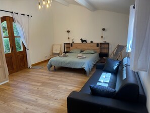 Une chambre à coucher avec un lit, un canapé, un plancher en bois, une fenêtre et une porte.