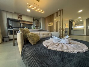 Una sala de estar moderna con un sofá, un tapete redondo y una cocina al fondo.