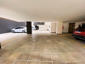 A parking garage with two cars parked, tiled floors, and pillars. - FlatFM20 CABO BRANCO Oceanview by Almare (João Pessoa)