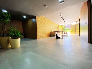 A spacious lobby with a modern design, featuring a large potted plant, a contemporary table, and a patterned wall. - FlatFM20 CABO BRANCO Oceanview by Almare (João Pessoa)