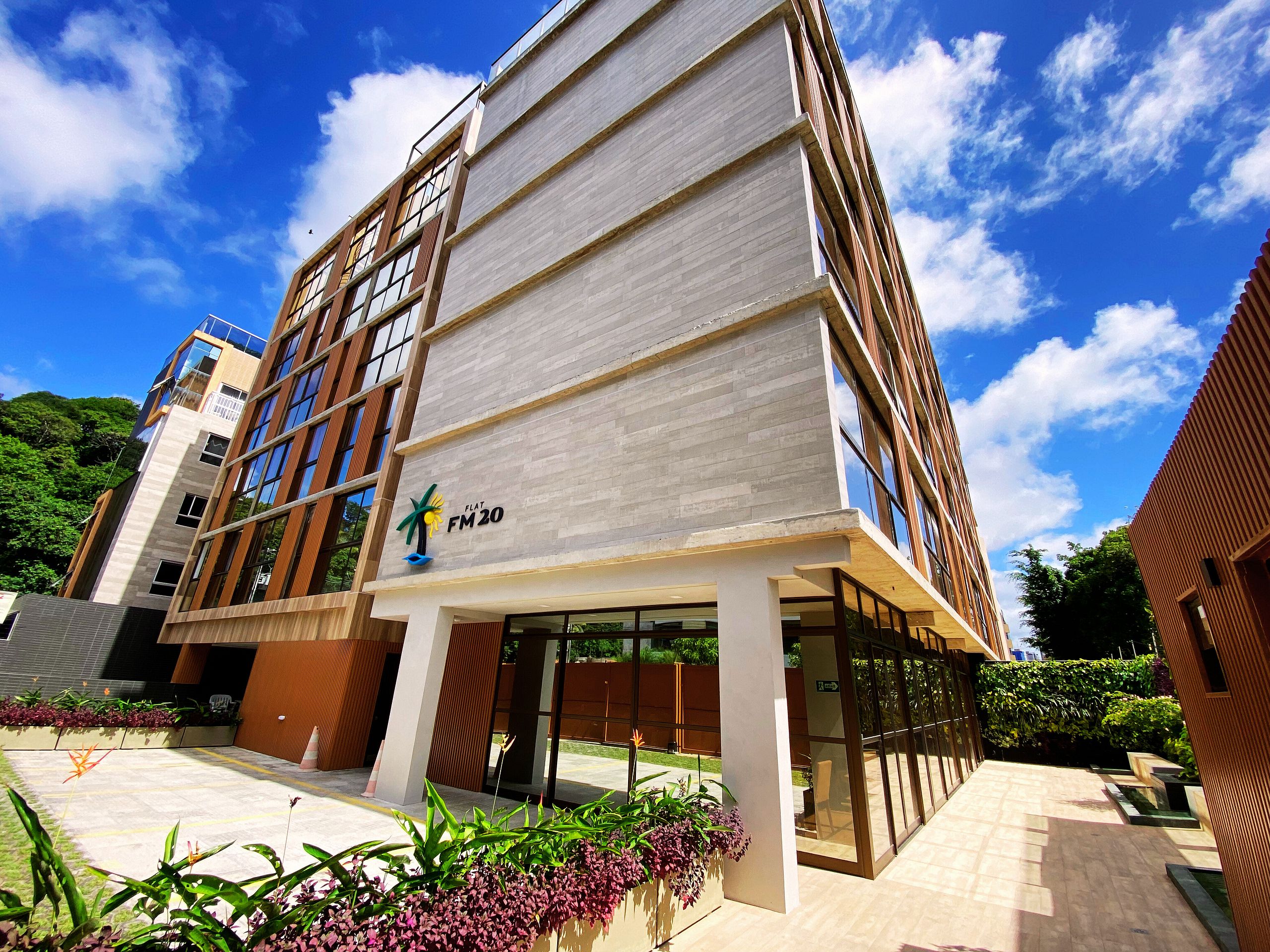 A modern building with a flat roof, large windows, and a sign reading "FLAT FM20".