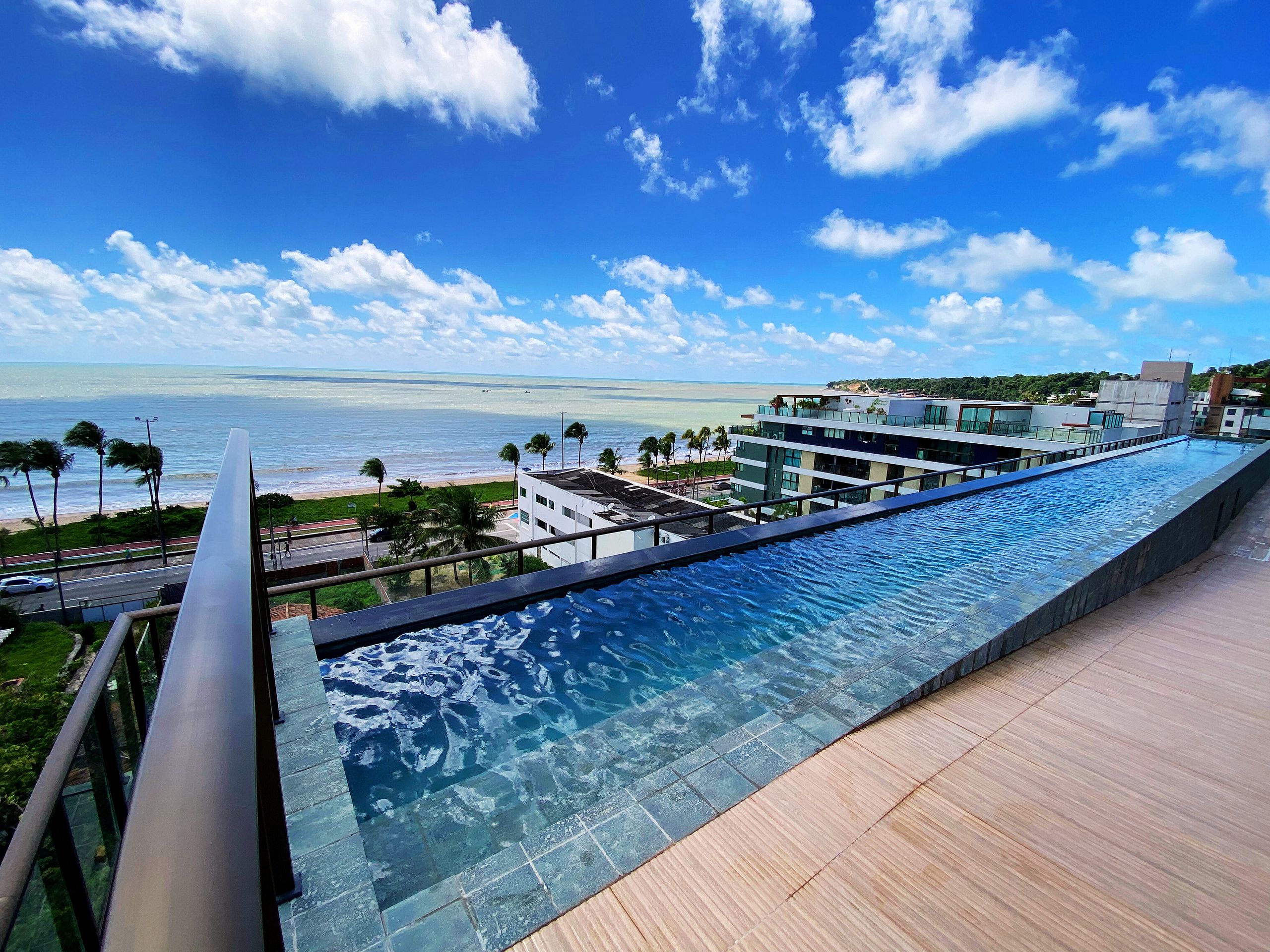 Une piscine à débordement moderne offrant une vue dégagée sur l’océan et la plage.