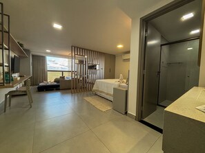 Una habitación de hotel moderna con cama, escritorio, silla, armario y zona de ducha.