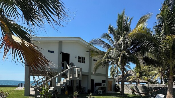 A swimming pool with a stone deck, surrounded by palm trees and a white building with a staircase. - breath taken ocean views,  just 25 minutes away  from the airport.  (SAN LUIS TALPA)