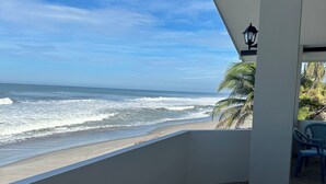A balcony with a view of the ocean, a stone floor, and a blue plastic chair. - breath taken ocean views,  just 25 minutes away  from the airport.  (SAN LUIS TALPA)