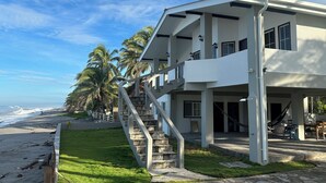 A modern two-story house with a stone staircase leading to a balcony, located near a beach with palm trees and ocean views. - breath taken ocean views,  just 25 minutes away  from the airport.  (SAN LUIS TALPA)