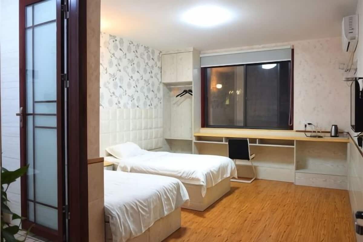 Une chambre avec deux lits, une fenêtre, un téléviseur et une armoire.