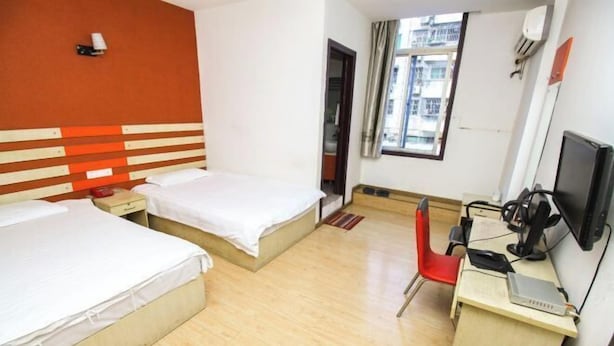 A hotel room with two beds, a desk with a computer, and a window with a view of buildings. - Haoyijia Express Hotel (Tongling People's Hospital) (Tongling)