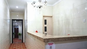A hotel reception area with a marble counter, a red carpeted hallway, and a chandelier. - Haoyijia Express Hotel (Tongling People's Hospital) (Tongling)