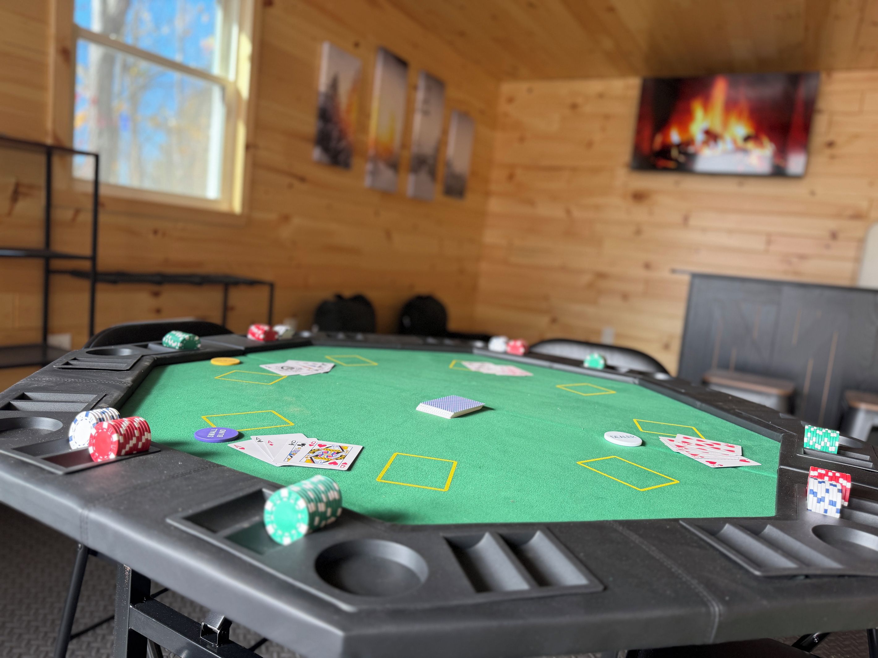 A poker table with chips and cards, wooden walls, and a fireplace.