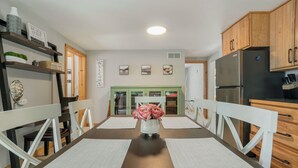 Eine moderne Küche mit Holzschränken, einem Edelstahlkühlschrank und einem Essbereich mit Tisch und Stühlen.