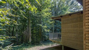Una cabaña de madera con un balcón que da a un área boscosa.