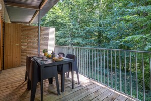 Um deck de madeira com mesa e cadeiras, com vista para uma área arborizada.