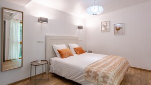 Un dormitorio con cama, una mesita de noche, un espejo y dos lámparas de pared.
