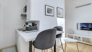 A modern kitchen with white cabinetry, a built-in coffee machine, and a flat-screen TV mounted on the wall. - L'Ormeau - Charmant appt (Toulouse)