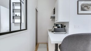 A compact kitchen with a white countertop, a coffee machine, and a framed picture on the wall. - L'Ormeau - Charmant appt (Toulouse)