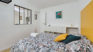 A bedroom with a bed, a bedside table, a mirror, and a painting on the wall. - L'Ormeau - Charmant appt (Toulouse)