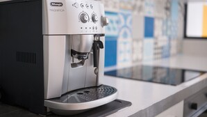 Una máquina de espresso De'Longhi MAGNIFICA sobre una encimera con un salpicadero de azulejos.
