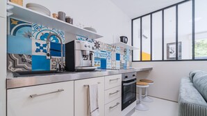 Una cocina moderna con armarios blancos, una cafetera y un ventanal amplio.
