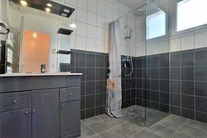 Enjoy a refreshing shower in the bathroom with a glass-enclosed shower, handheld showerhead, and large mirror.