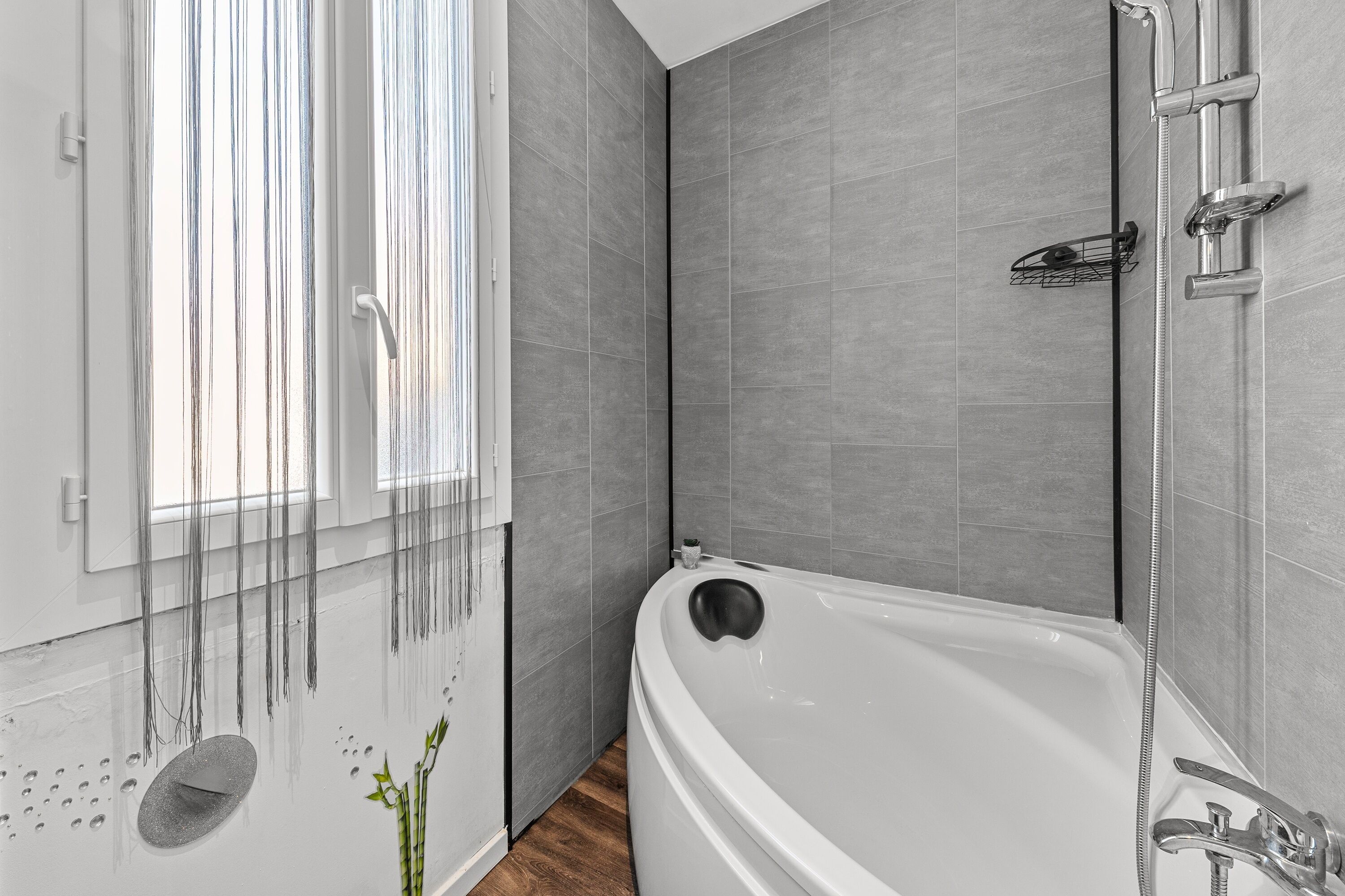 A modern bathroom with a freestanding bathtub, a shower area, and a window with vertical blinds.