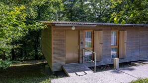 Eine kleine Holzhütte mit Tür, Fenstern und einer Rampe, die zum Eingang führt.