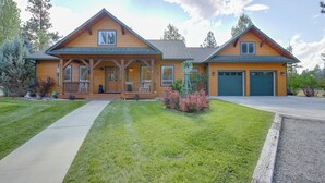A two-story house with a front porch, a garage, and a well-maintained lawn. - Clark Fork Riverfront Home w/ Dock! (Thompson Falls)