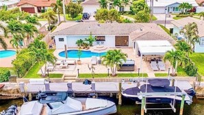 A residential area with a swimming pool, boats docked at the marina, and palm trees.