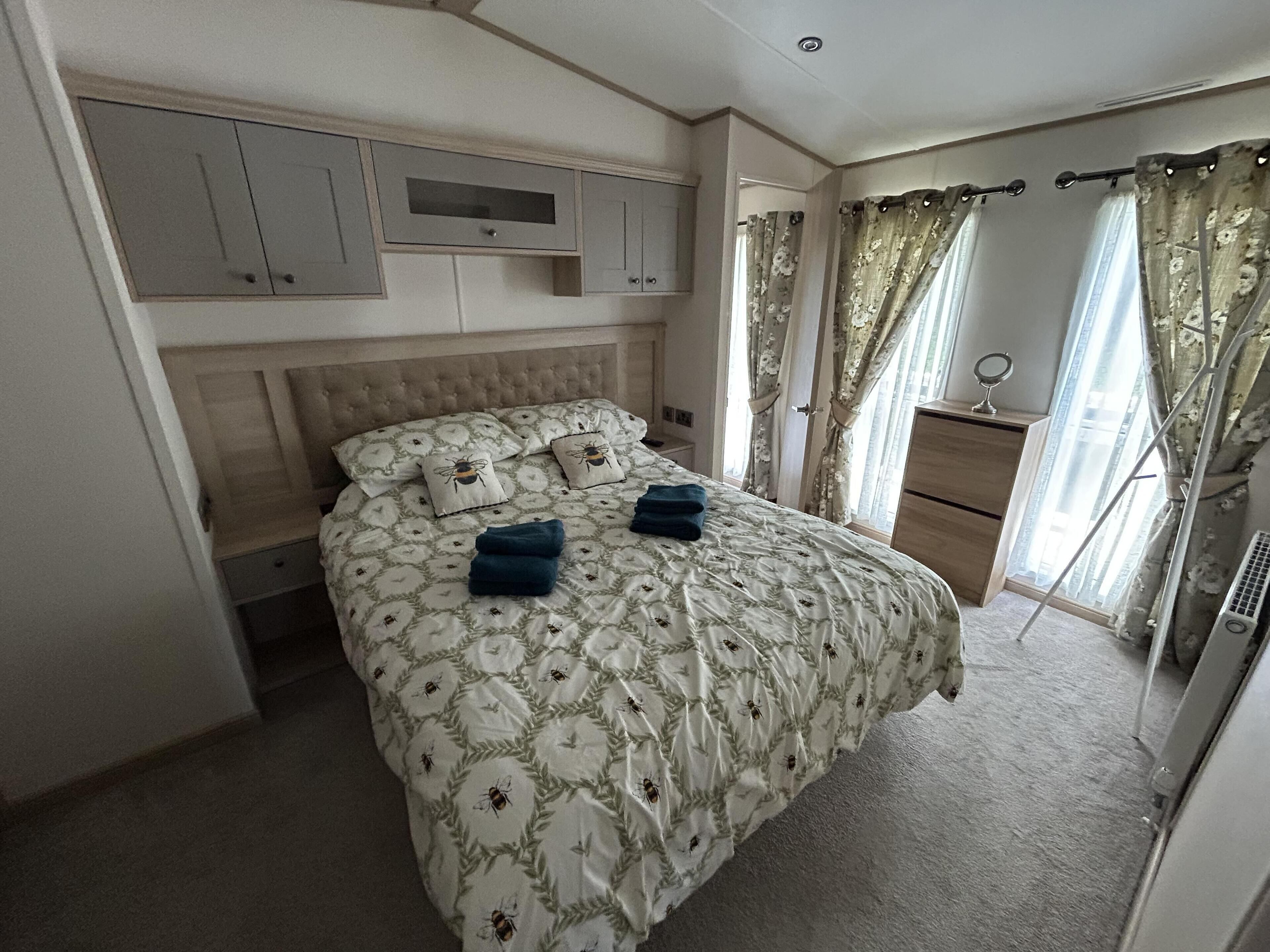 A bedroom with a bed, a nightstand, a dresser, and a window with curtains.