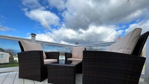 Terraza con mobiliario de mimbre y vista a una casa al fondo.