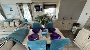 Un espacio de sala acogedor con un sofá, una mesa de comedor con cuencos morados y un jarrón de flores.