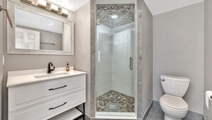 A bathroom with a white vanity, a glass-enclosed shower, and a toilet. - Downtown TC Two Unit Retreat on the Water - Sleeps 10 (Traverse City)