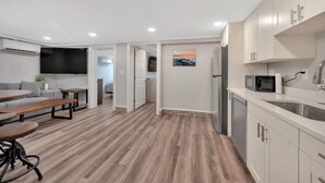 A modern kitchen with white cabinets, a stainless steel sink, and a microwave. - Downtown TC Two Unit Retreat on the Water - Sleeps 10 (Traverse City)