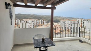 En balkong med utsikt över ett bostadsområde och kullar.