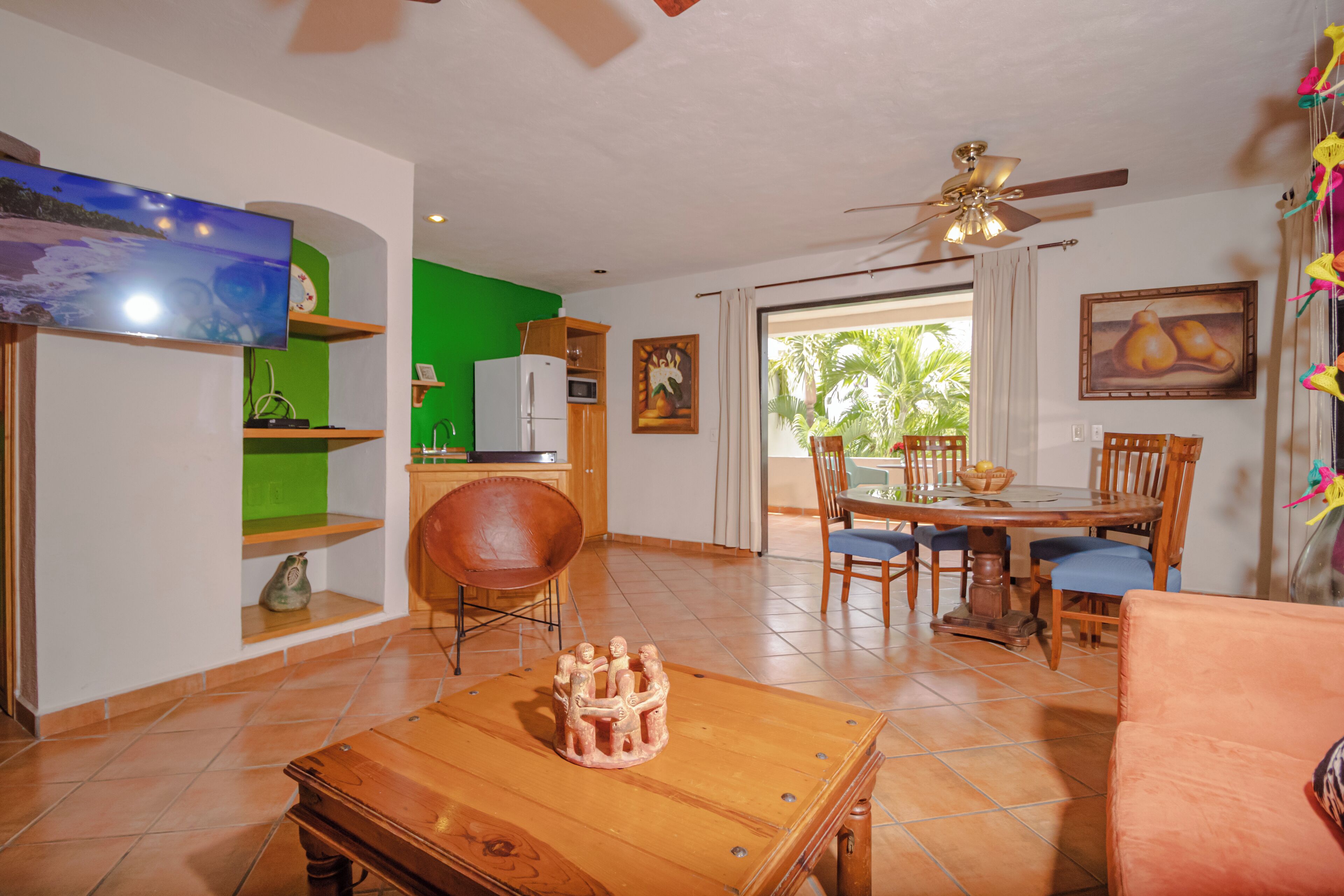 Una sala de estar con televisión, muebles de madera, un comedor y vistas al exterior.