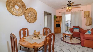 A living room with a dining table, chairs, a sofa, a ceiling fan, and a TV. - Villas Mi Mexico (Bucerías)