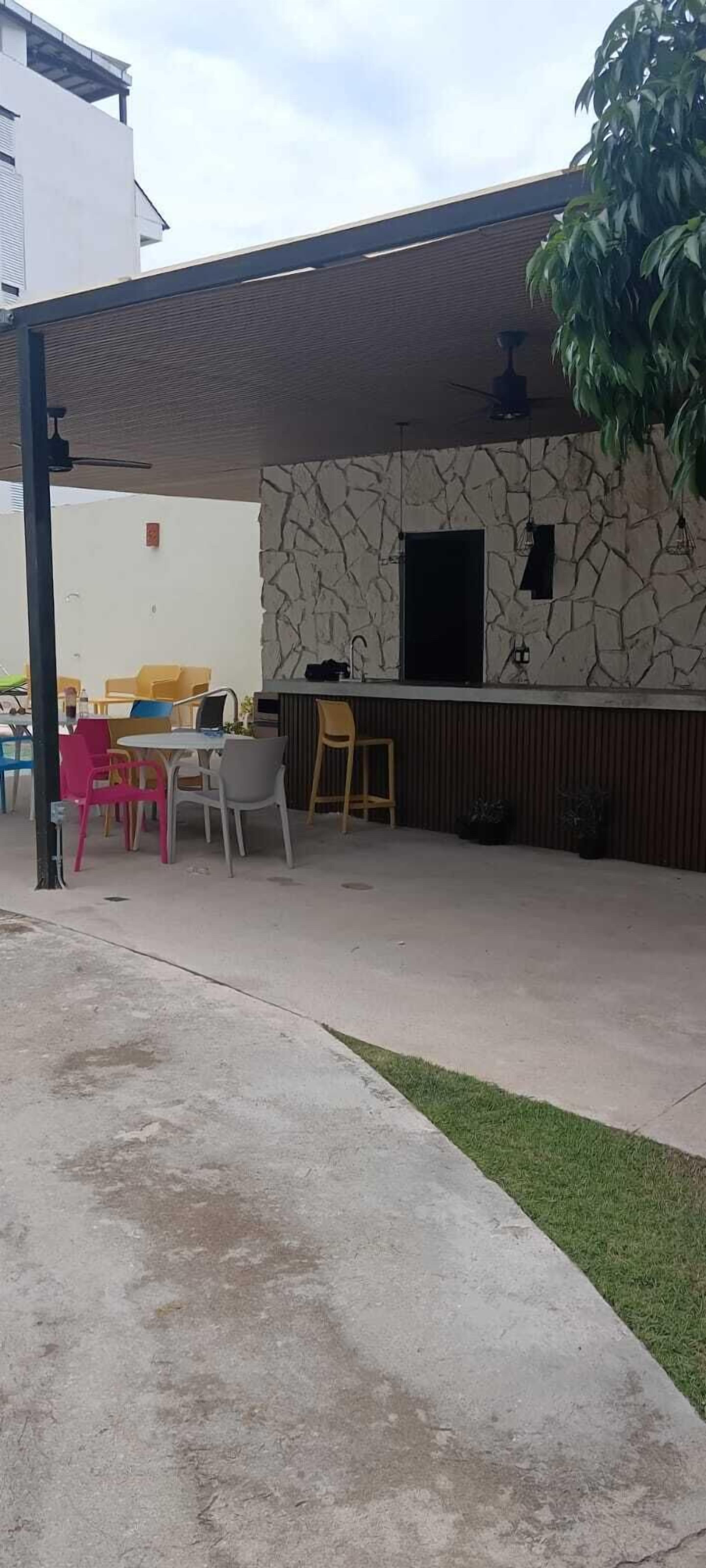 Un patio al aire libre con zona de estar techada, un muro de piedra y una barra.